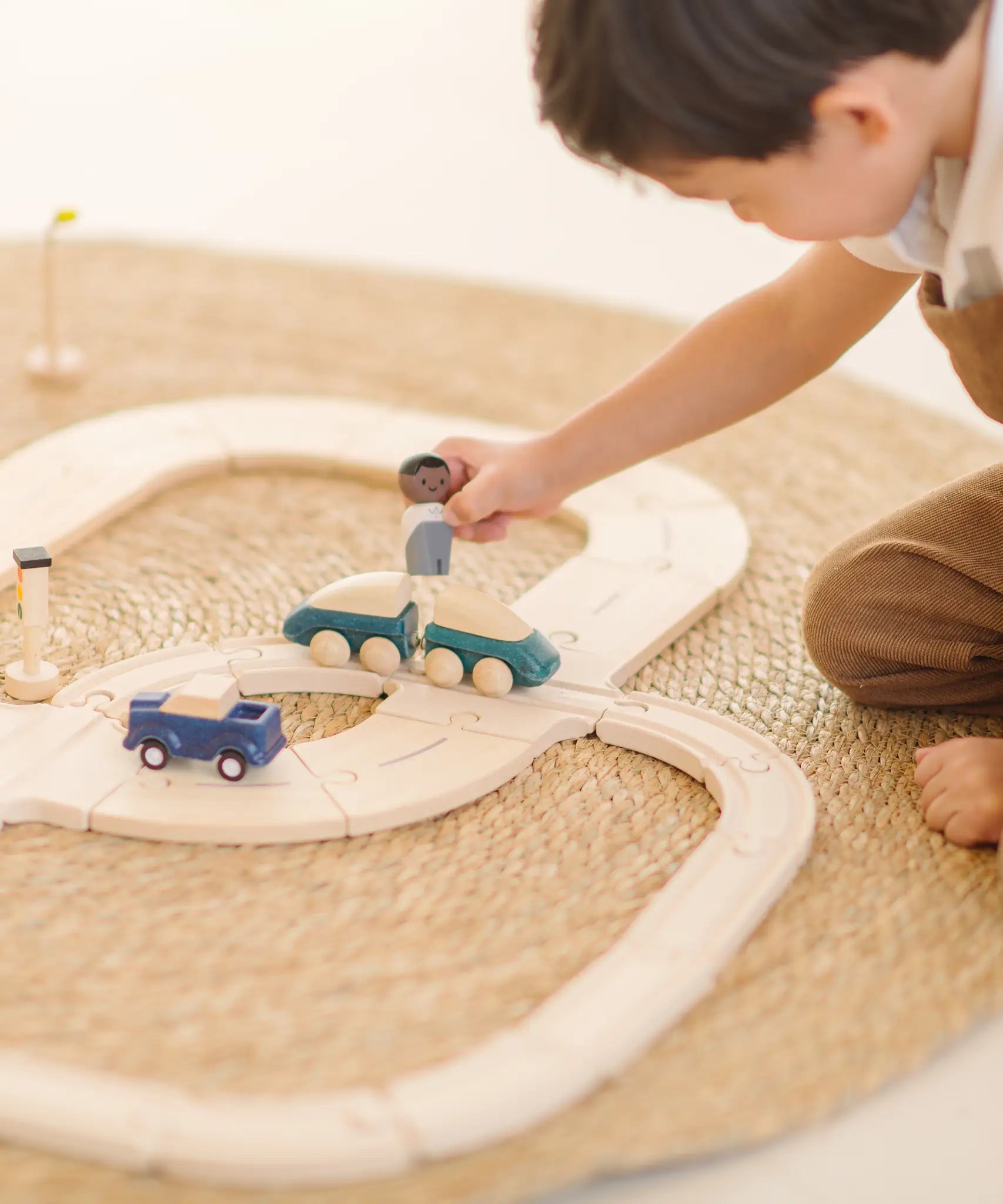 Child playing with the PlanToys my first wooden rail road set holding wooden man figure above a train