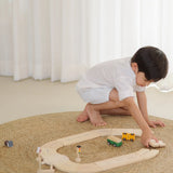 Child building a ring road using the road pieces from the PlanToys my first road way set