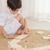 Child assembling the wooden road pieces from the PlanToys my first roadway set