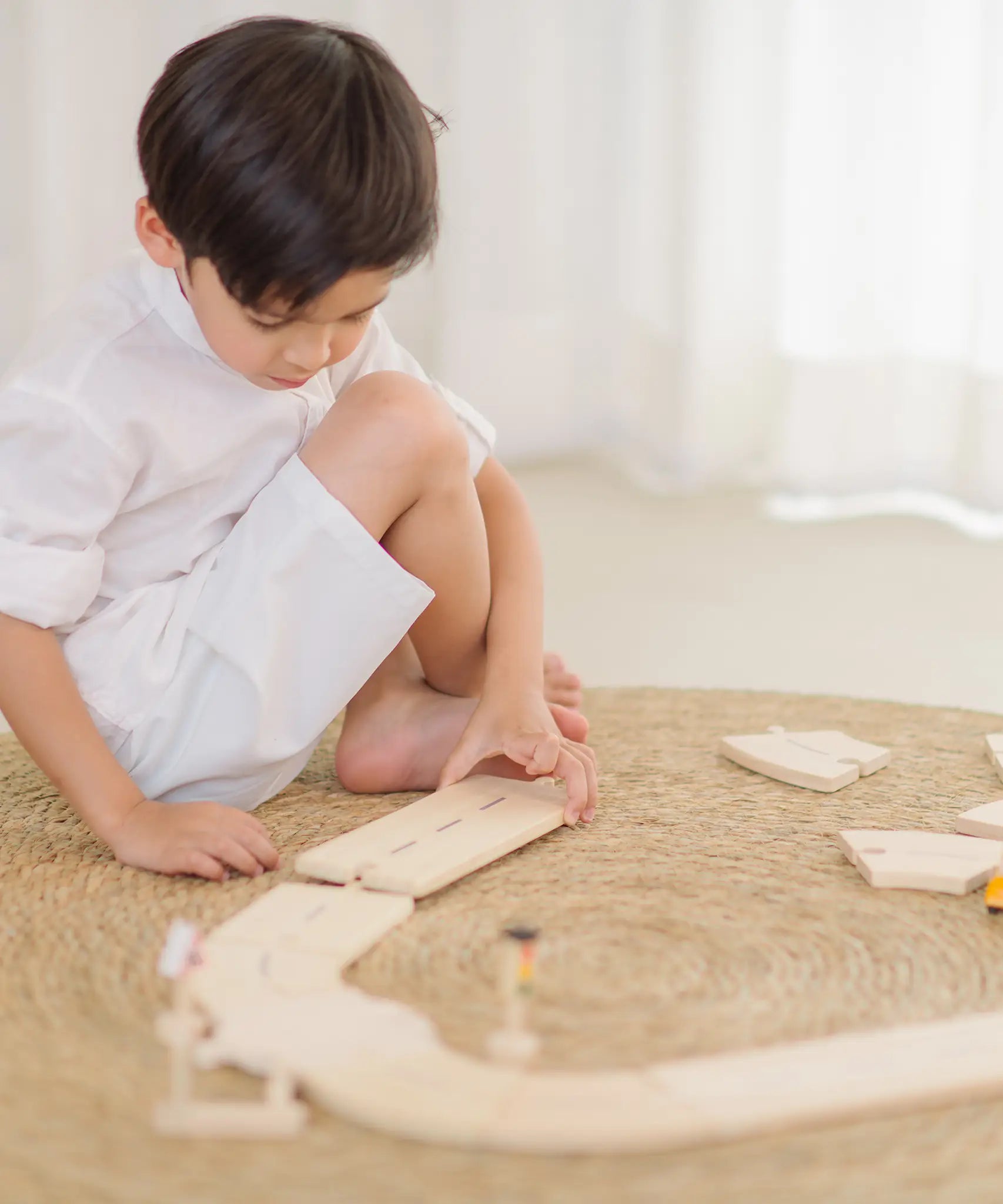 Child assembling the wooden road pieces from the PlanToys my first roadway set