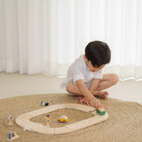 Child holding a green vehicle playing on the PlanToys my first roadway set 