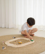 Child holding a green vehicle playing on the PlanToys my first roadway set 