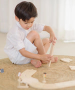 Child holding a loose wooden road piece from the PlanToys my first roadway set 