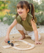 Child pushing a train on the wooden rail pieces from the PlanToys my first train set