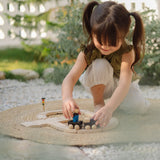 Child playing with a train from the PlanToys my first train set on a woven rug in the garden