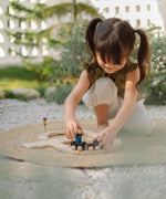 Child playing with a train from the PlanToys my first train set on a woven rug in the garden