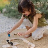 PlanToys my first train set on a woven rug with a child holding a wooden figure