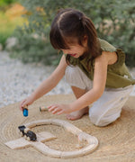 PlanToys my first train set on a woven rug with a child holding a wooden figure