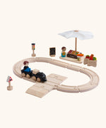A PlanToys my first train set showing a market stall set standing next to the wooden rails