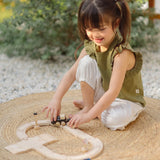 Child playing with the PlanToys my first train set on a woven rug in the garden