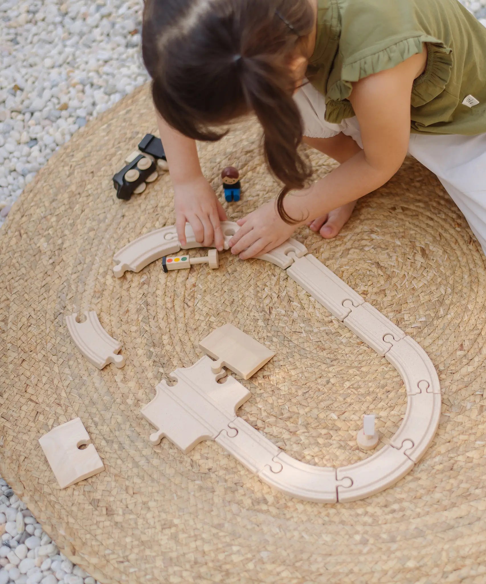 Child assembling a rail road using pieces fro the PlanToys my first train set 