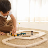 Child holding a yellow car on the wooden road piece from PlanToys  my first rail road playset