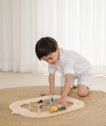 Child playing with the PlanToys my first wooden roadway set on a rug