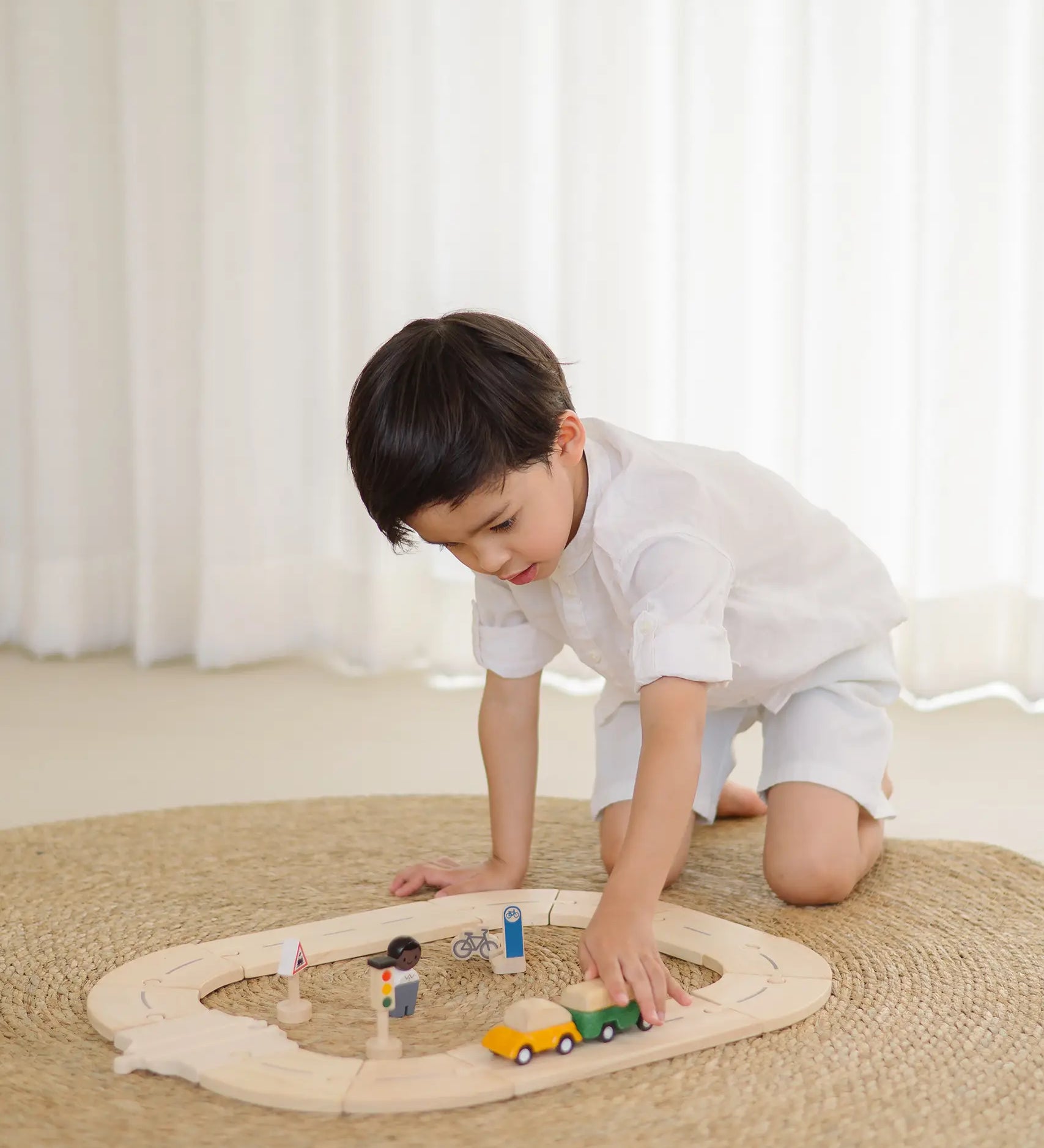 Child playing with the PlanToys my first wooden roadway set on a rug