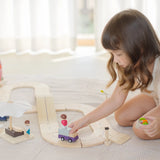 Child playing with a purple truck on the PlanToys wooden road pieces