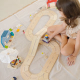 Child playing with the PlanToys my little wooden neighbourhood play set on a white blanket