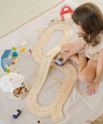 Child playing with the PlanToys my little wooden neighbourhood play set on a white blanket