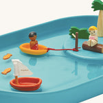 A closer look at the figures in the PlanToys Water Play Set relaxing on the raised island and in a yellow boat