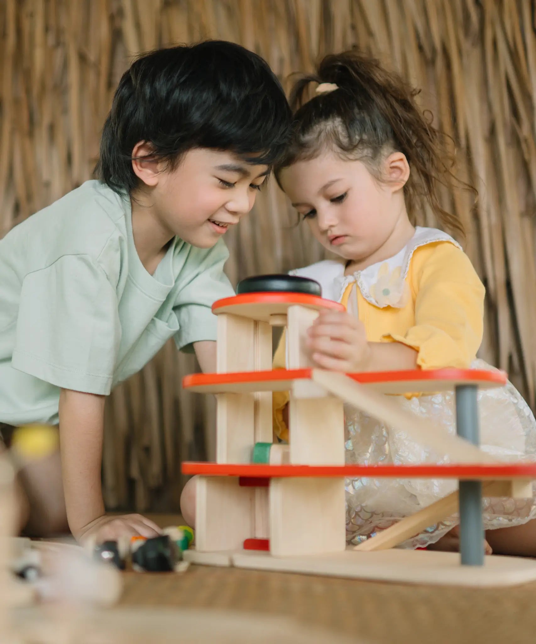 Children playing with the PlanToys wooden city parking garage using the wind up lift