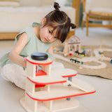 Child using the wind up lift on the PlanToys wooden city parking garage to move a vehicle