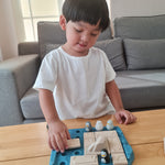 Close up of a child picking up a rectangle piece from the Plan Toys eco-friendly wooden finding penguin game on a wooden table