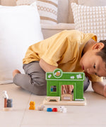Child arranging different accessories on the PlanToys wooden pet shop