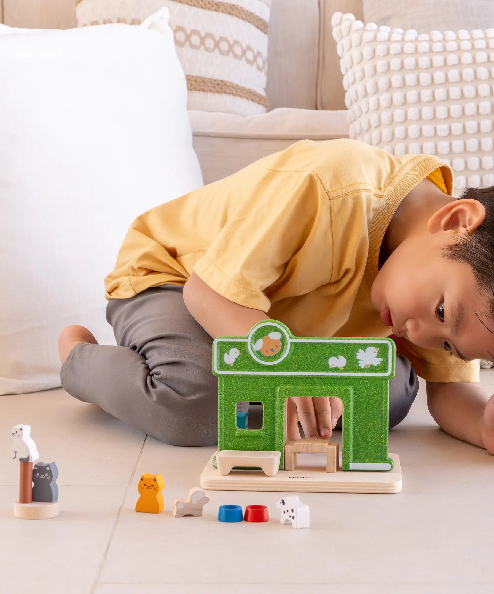 Child arranging different accessories on the PlanToys wooden pet shop