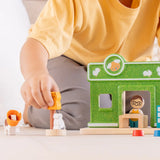 Child holding a cat figure next to a PlanToys pet shop play set showing scale