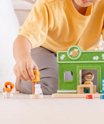 Child holding a cat figure next to a PlanToys pet shop play set showing scale