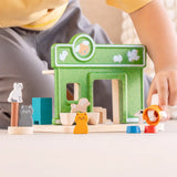 Child holding a dog figure next to the PlanToys wooden  pet shop play set