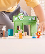 Child holding a dog figure next to the PlanToys wooden  pet shop play set