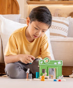 Child holding a shop keeper figure next to a PlanToys pet shop play set showing scale 