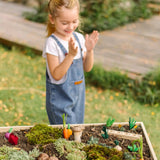 An empty PlanToys seedling patch with loose wooden veg pieces scattered on a large planter