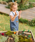 An empty PlanToys seedling patch with loose wooden veg pieces scattered on a large planter