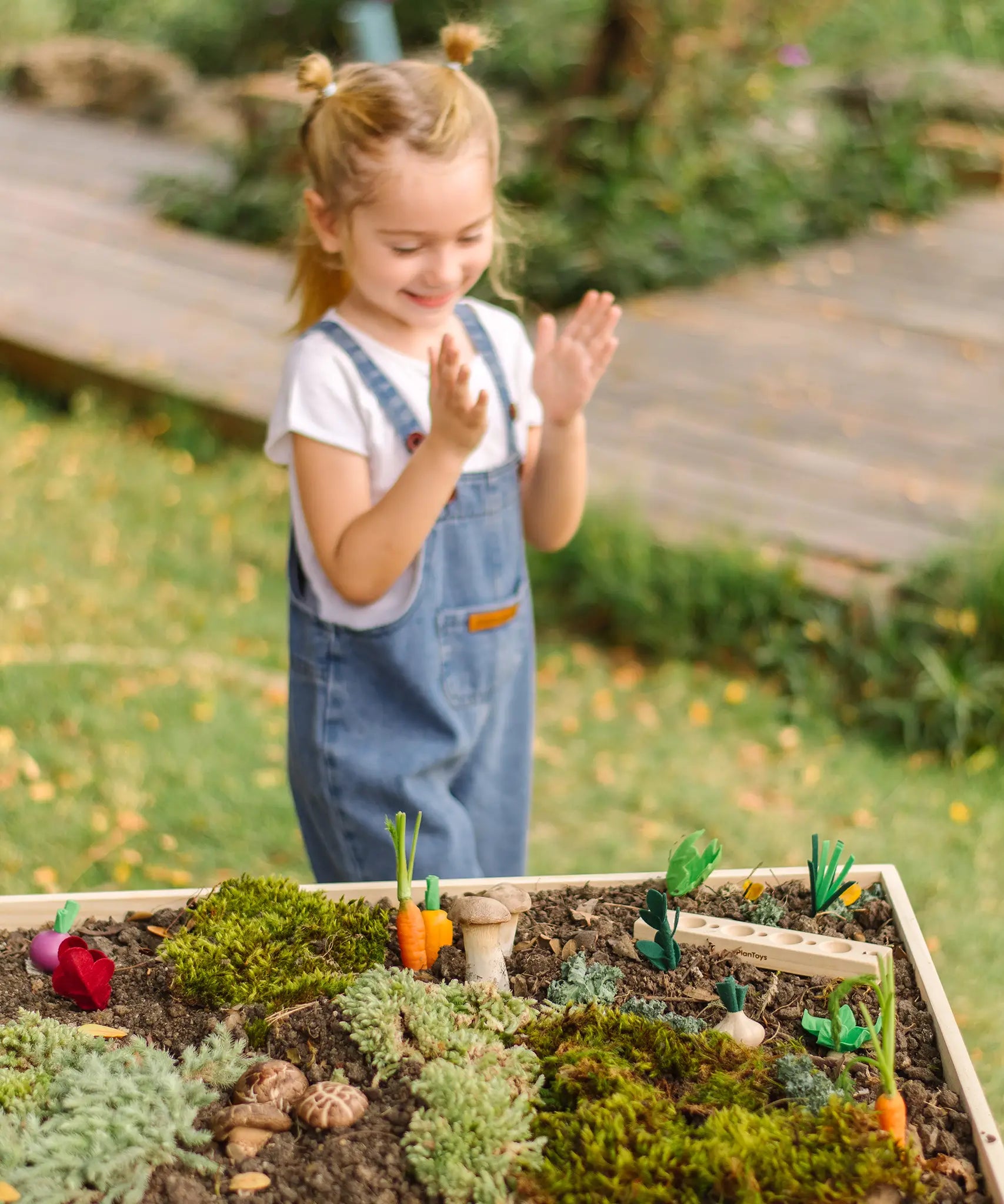 An empty PlanToys seedling patch with loose wooden veg pieces scattered on a large planter
