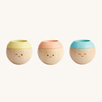 The PlanToys Pastel Sensory Tumbling balls are great for babies and little ones. These adorable balls have a happy, smiling face on the front. The left ball has a yellow top, the middle ball has a peach top, and the right ball has a blue top.