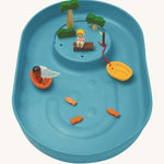 A top view of the PlanToys Water Play Set without water. The inside of the blue tray is textured to give a fun sensory experience, the little fish, boats and people are in the tray. The image is on a cream background
