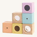 The PlanToys Activity Blocks set, is a wonderful, sensory experience for babies and toddlers. 6 different coluored blocks come with their own sensory part, which includes a differnt texture, sound and colour. These blocks can also be used for stacking games. The image is on a cream background.