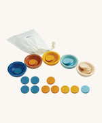 PlanToys Sort & Count Cups are a fun and educational toy for children. In the set are 5 bowls, in blue, orange, yellow, light blue and white, with 5 round disks for each bowl in the same colours. The image is on a cream background.