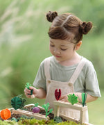 Planting beds from the PlanToys stack & sprout set with a child inserting loose veg pieces