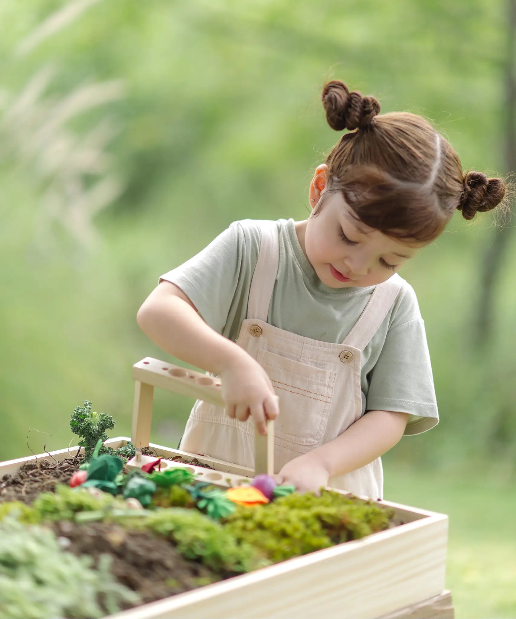 Child building planting beds using pieces from PlanToys stack and sprout set on a large planter