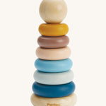 The PlanToys Stacking Rings are a fun and educational toy for children. The set comes with 6 rings in shades of blue, peach and yellow, and has a removable ball on the top that can be rolled on the ground or put inside the ring holes. The image is on a cream backround.