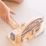 Child inserting a wooden rail road piece on the PlanToys train station using a connector