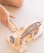 Child inserting a wooden rail road piece on the PlanToys train station using a connector