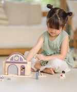 Child playing with the PlanToys wooden train station on its own.