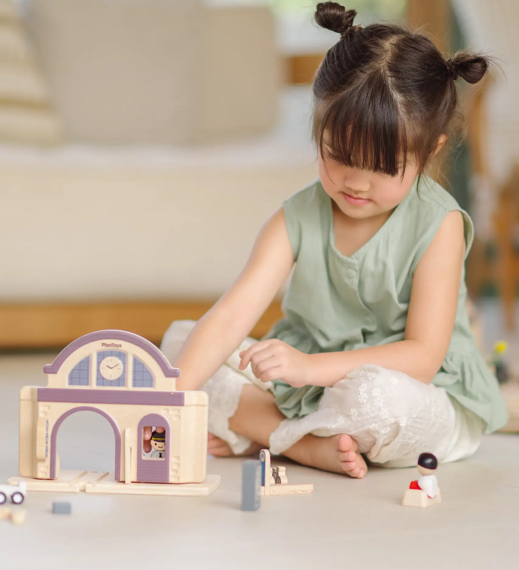 Child playing with the PlanToys wooden train station on its own.