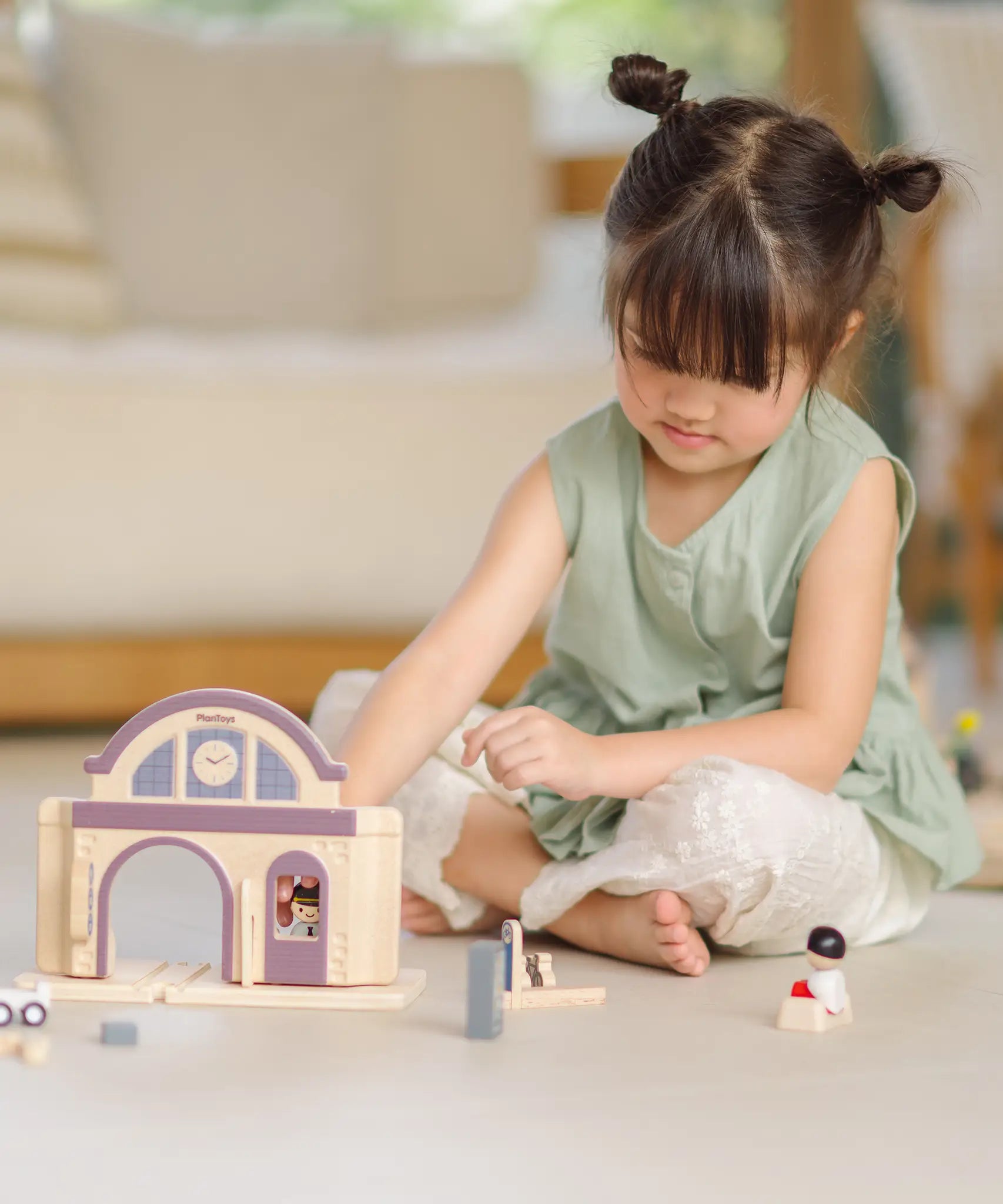Child playing with the PlanToys wooden train station on its own.
