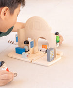 Back of the PlanToys train station showing the rail piece running underneath. Child holding people figures