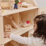 PlanToys Victorian dolls house with small furniture and dolls inside and a child sitting near