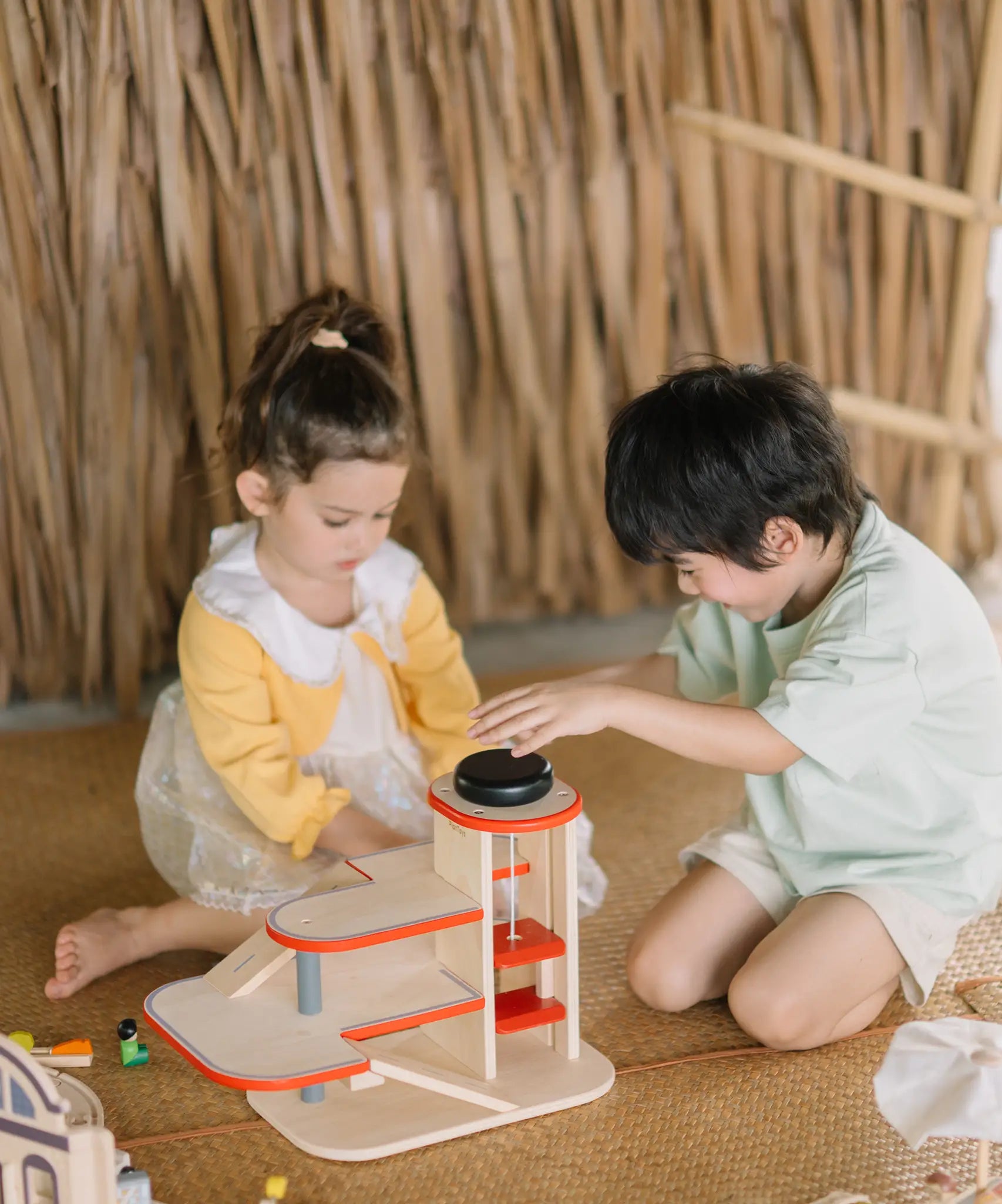 Children playing with the PlanToys wooden city parking garage 